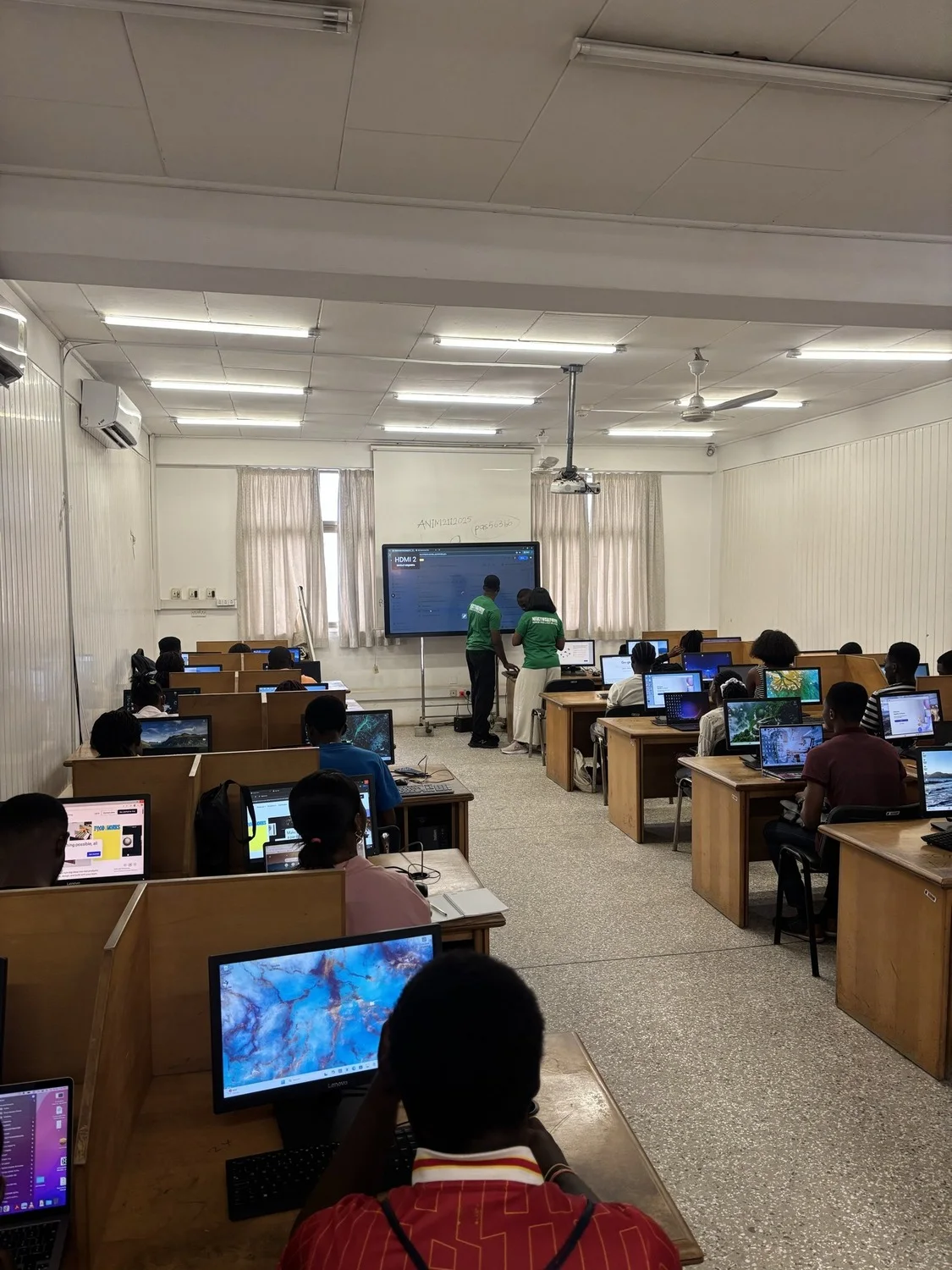 A wide view down the computing lab, every workstation occupied by participants.