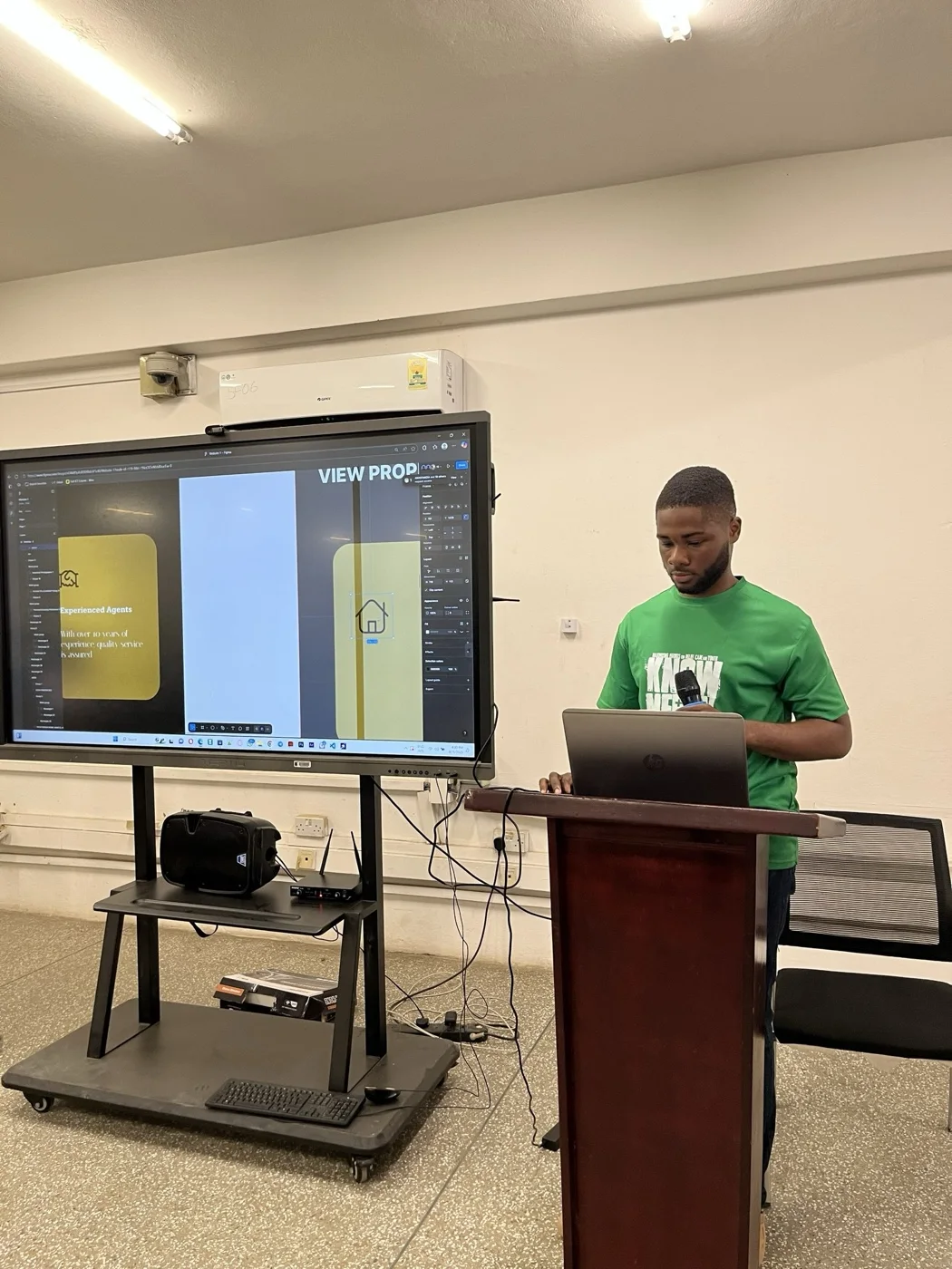 A facilitator presenting a web design walkthrough in Figma on a large screen.