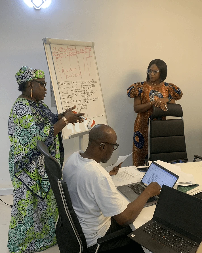 A facilitator working through a planning grid on a flip chart while participants follow on laptops.