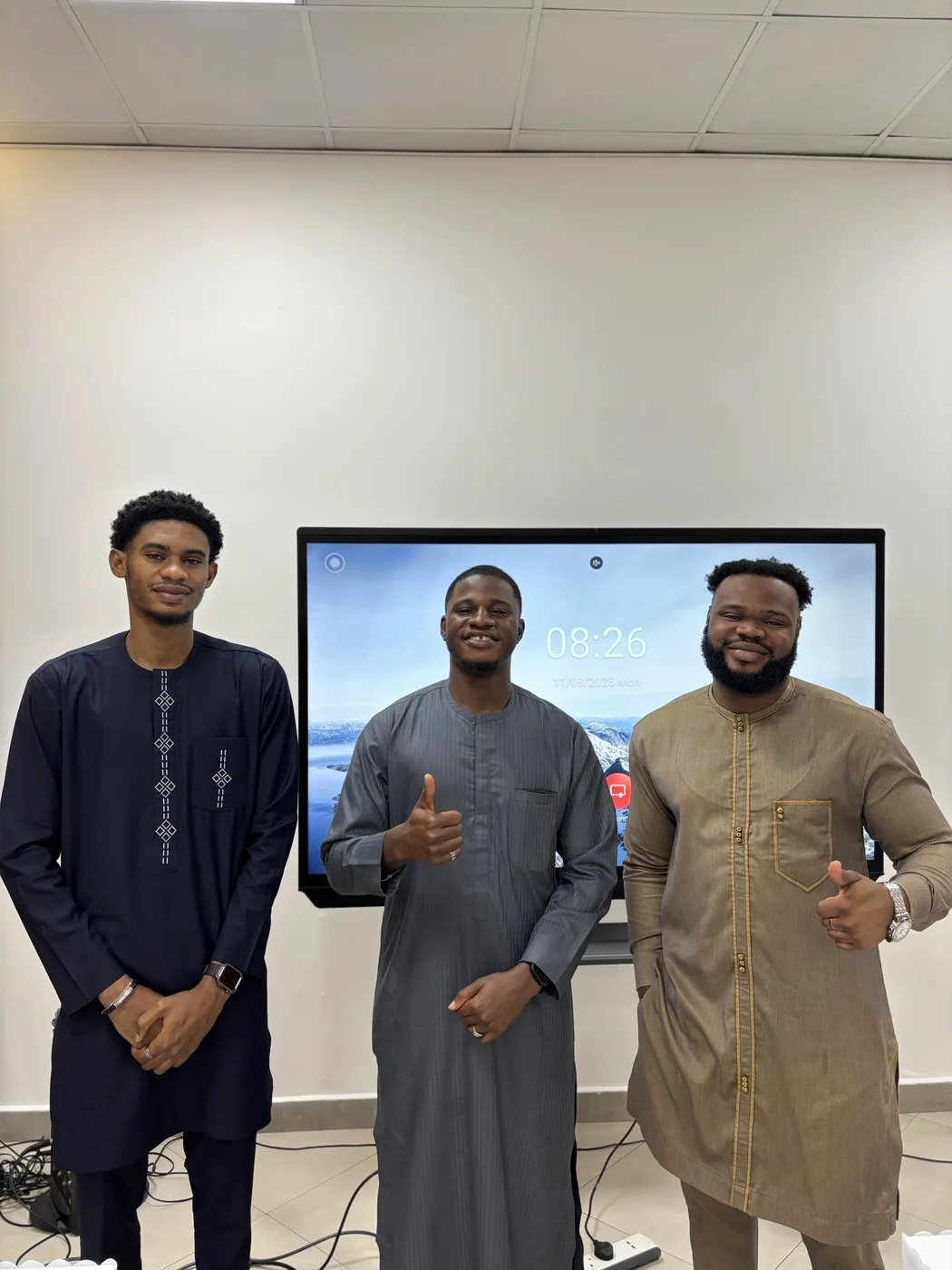 Three members of the Timalytics team at a training venue in front of a presentation screen.