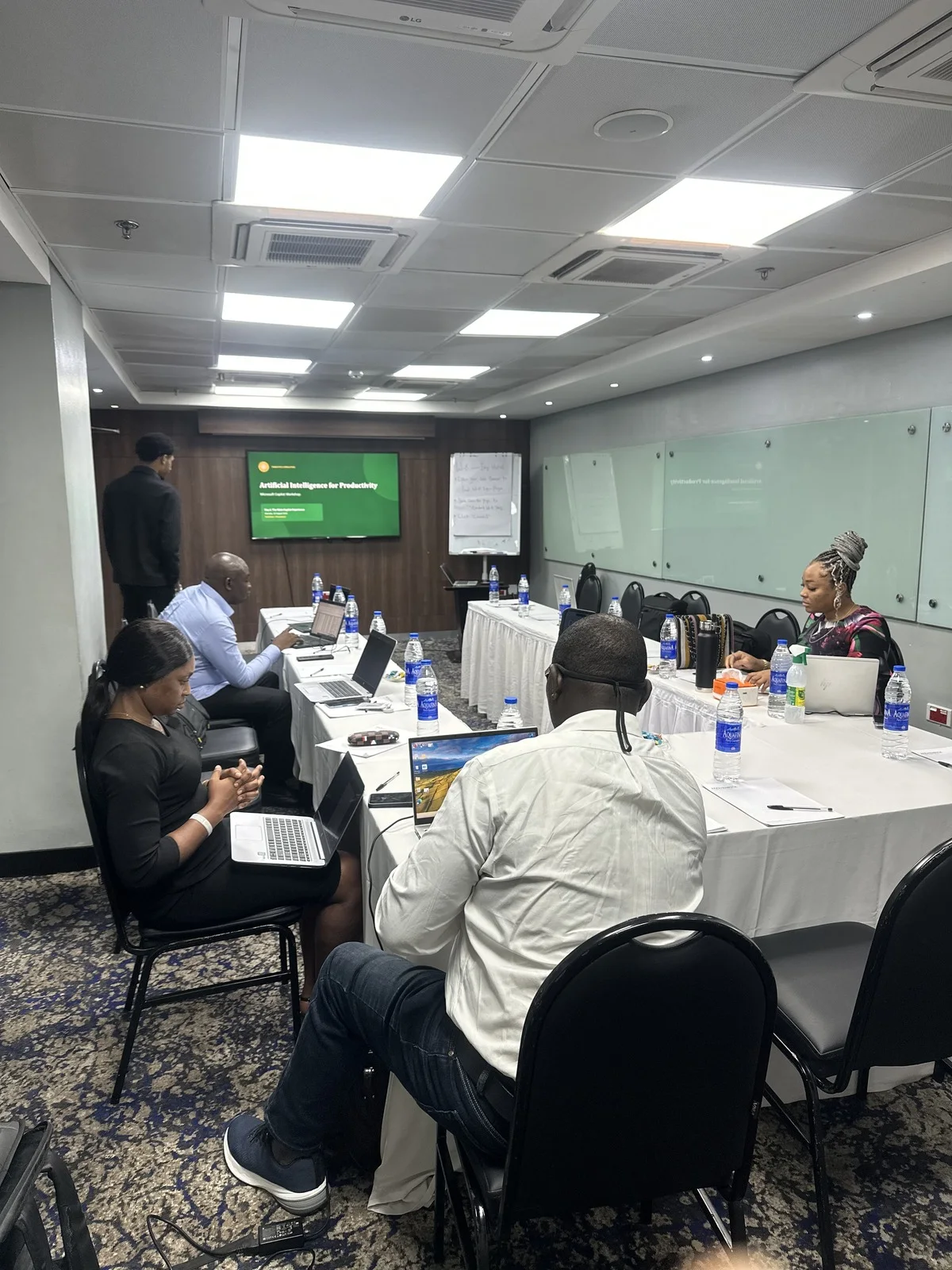 An Artificial Intelligence for Productivity workshop under way, participants at laptops around a boardroom table.